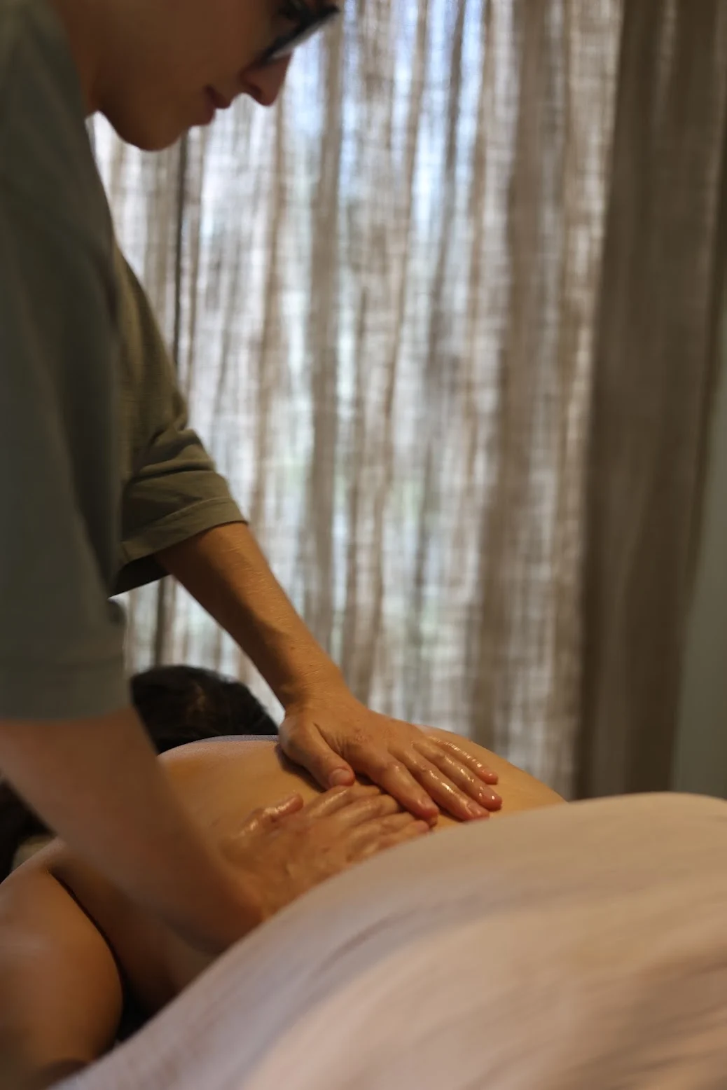 Astrid geeft een rugmassage in een rustige, warm verlichte ruimte